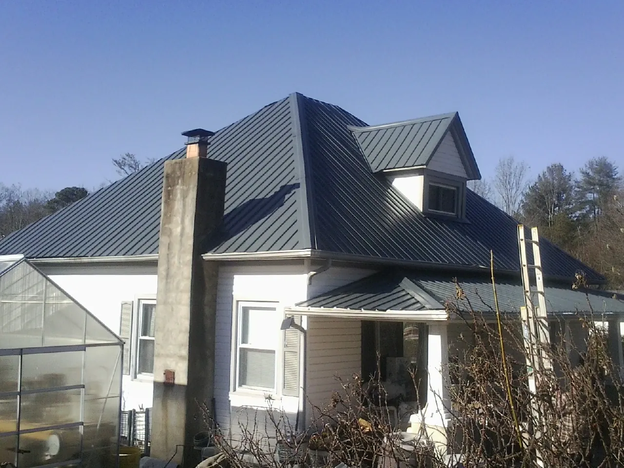 Dark blue standing seam metal roof on a white farmhouse with dormer — Slate & Tile Roof Repair by Roofing Brothers in Ballantine