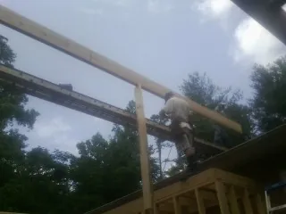 Carpenter setting a ridge beam over a new addition frame — Ice Dam Removal by Roofing Brothers in Ballantine