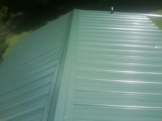 New green metal panels meeting at the ridge of a roof — Flat Roof Repair work by our crew in Ballantine