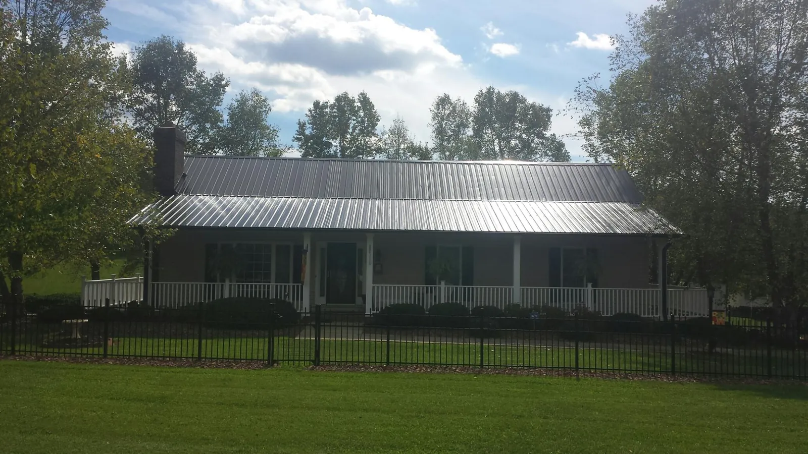 Gray metal roof on a brick ranch with a full width front porch — Gutter Guard Installation work by our crew in Ballantine
