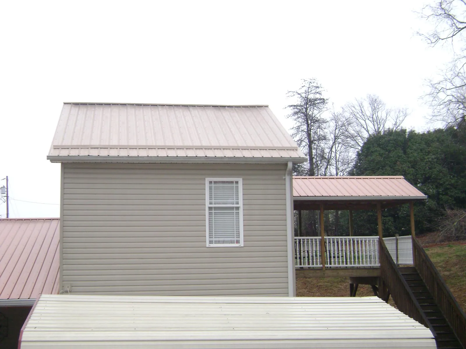 Tan metal roofs on a two story addition and attached porch, from a Roof Replacement job in Ballantine